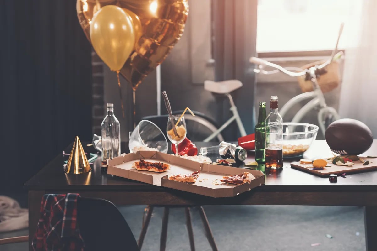 messy student flat with pizza boxes and drinks